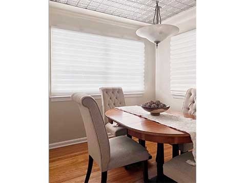 Bright dining room space with two windows covered by Duette shades