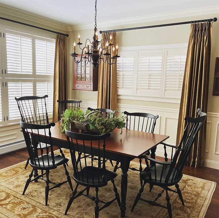 Dining room table with a basket full of flowers on top, surrounded black chairs